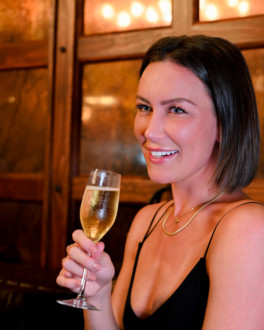 Woman enjoying champagne at Flute & Dram on Beach Drive in St. Petersburg, Florida
