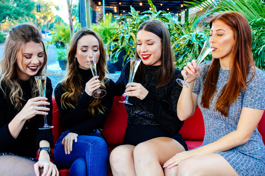 Four women sipping champagne outside at Flute & Dram on Beach Drive in St. Petersburg, Florida