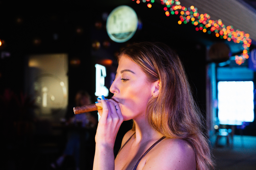 Bella Mangiafico smoking a cigar outside at Flute & Dram on Beach Drive in St. Petersburg, Florida